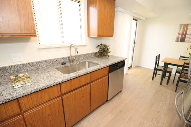 40831 Highpointe Dr, Clinton Township, MI 48038 - kitchen with stainless steel dishwasher, a sink, light wood-style flooring, light stone counters, and brown cabinetry