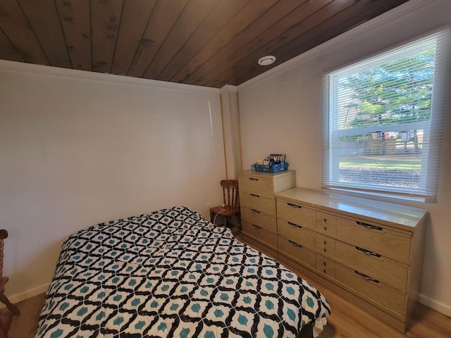 bedroom with light hardwood / wood-style flooring, wooden ceiling, and ornamental molding