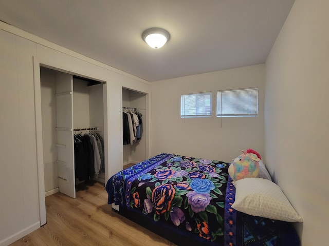 bedroom with wood-type flooring and two closets