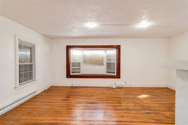 spare room featuring a textured ceiling, wood-type flooring, and baseboard heating