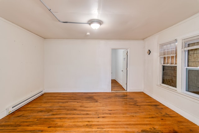 spare room with baseboard heating, ornamental molding, and light wood-type flooring