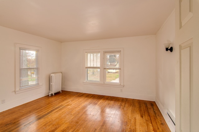 unfurnished room featuring radiator heating unit, hardwood / wood-style flooring, and baseboard heating