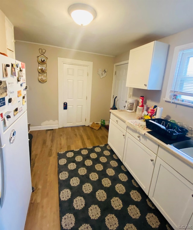 kitchen with white cabinets, white refrigerator, and light hardwood / wood-style flooring