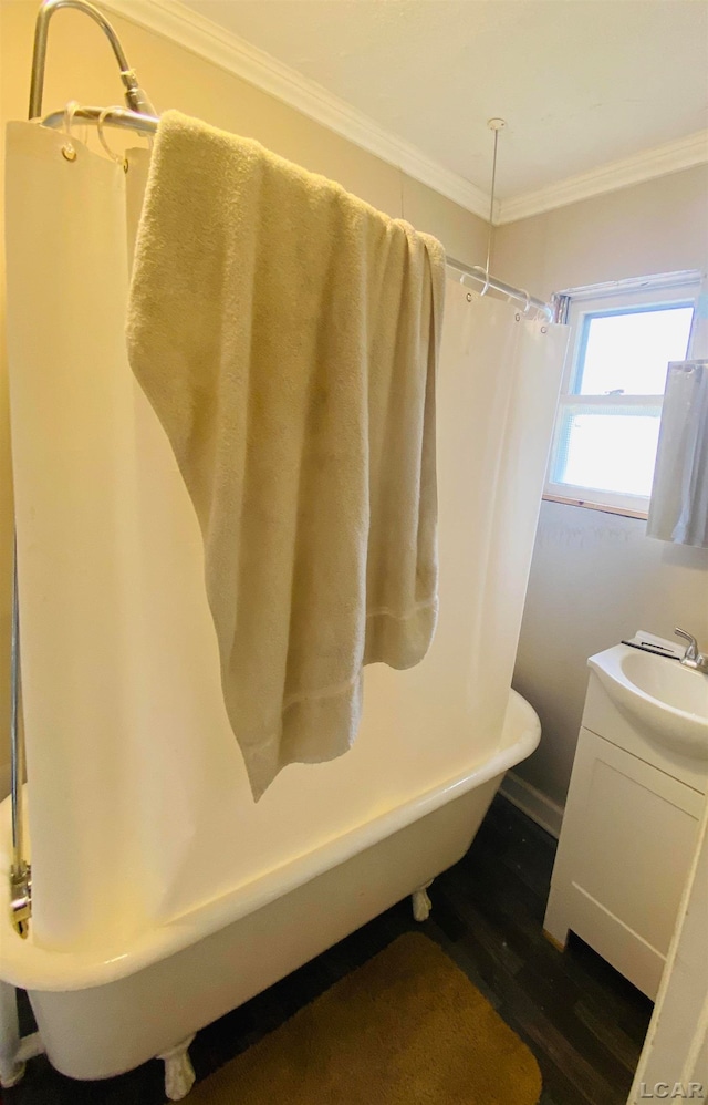 bathroom featuring a tub, hardwood / wood-style floors, vanity, and ornamental molding