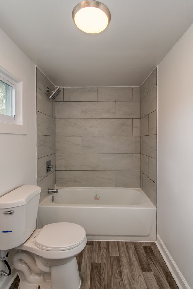 bathroom with toilet, tiled shower / bath, and hardwood / wood-style flooring