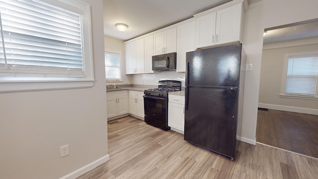 kitchen with black appliances, white cabinets, sink, light hardwood / wood-style flooring, and decorative backsplash