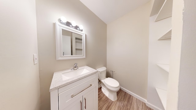 bathroom featuring hardwood / wood-style flooring, vanity, toilet, and vaulted ceiling