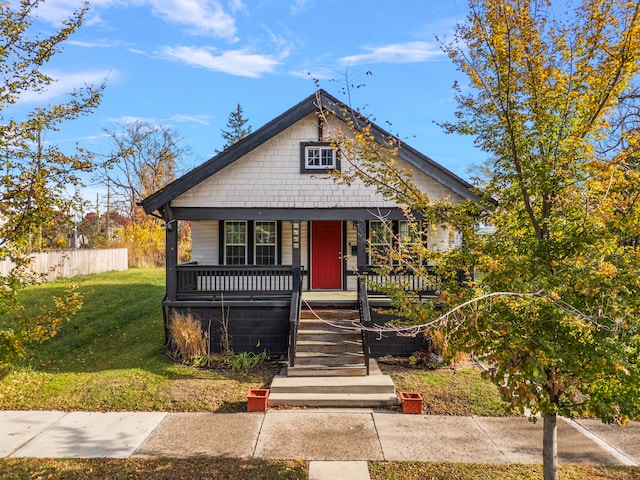 bungalow featuring covered porch and a front yard