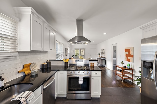 kitchen featuring exhaust hood, kitchen peninsula, appliances with stainless steel finishes, dark hardwood / wood-style flooring, and white cabinetry