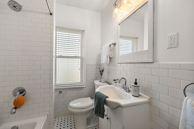 full bathroom featuring tiled shower / bath, vanity, toilet, and tile walls