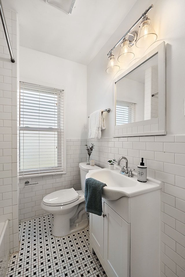 2552 Beals St, Detroit, MI 48214 - full bath featuring tile walls, toilet, vanity, healthy amount of natural light, and tile patterned flooring