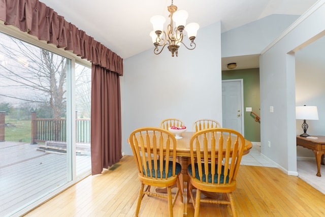 dining space with light hardwood / wood-style flooring, a chandelier, and vaulted ceiling