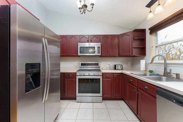 kitchen featuring stainless steel appliances, vaulted ceiling, sink, light tile patterned floors, and decorative light fixtures