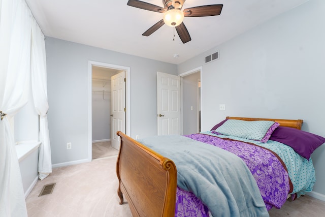 carpeted bedroom with ceiling fan, a spacious closet, and a closet