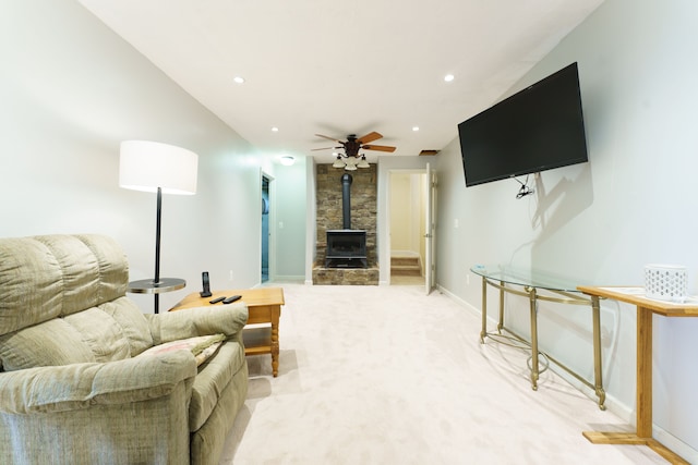 living room featuring a wood stove, ceiling fan, and carpet floors