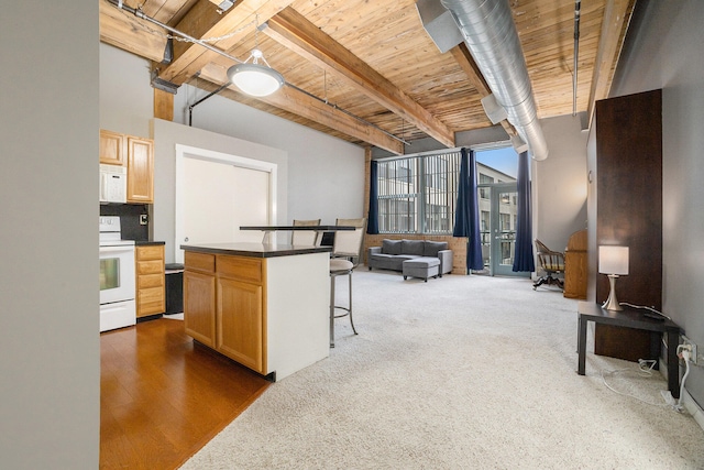 kitchen with beam ceiling, light brown cabinets, white appliances, a breakfast bar area, and a kitchen island