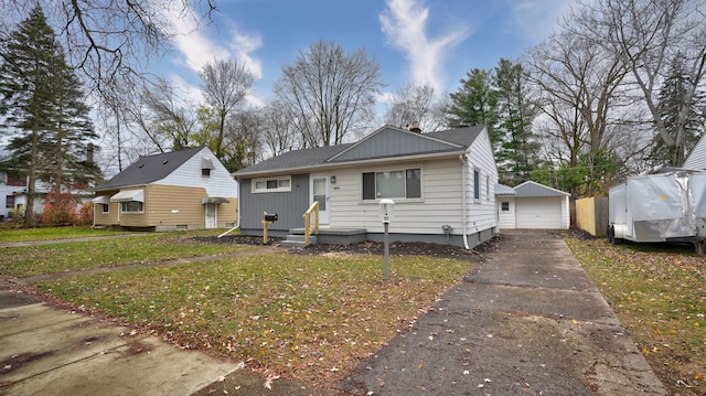 bungalow-style home with a garage, a front lawn, and an outdoor structure