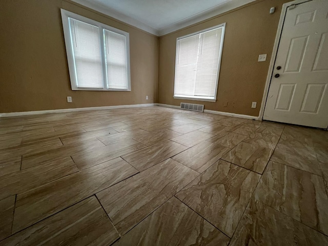 spare room with baseboards, ornamental molding, and visible vents