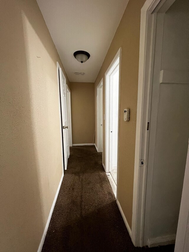 hallway featuring baseboards and carpet flooring