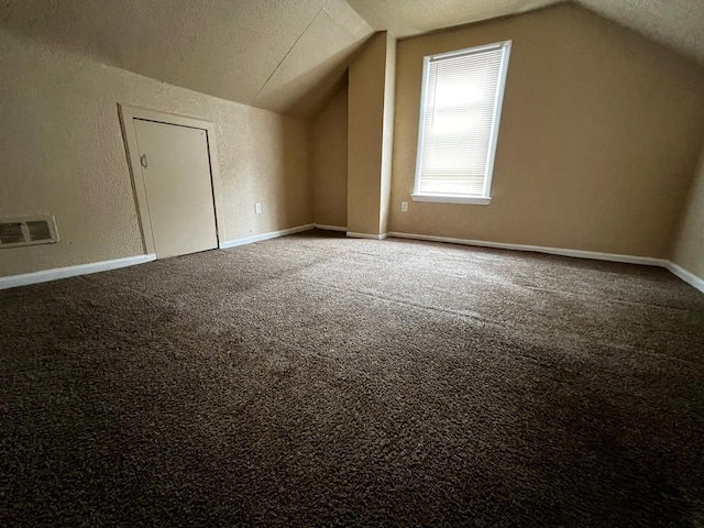 bonus room with a textured wall, carpet, visible vents, and lofted ceiling