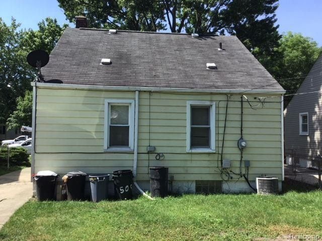 back of house with a lawn and central AC