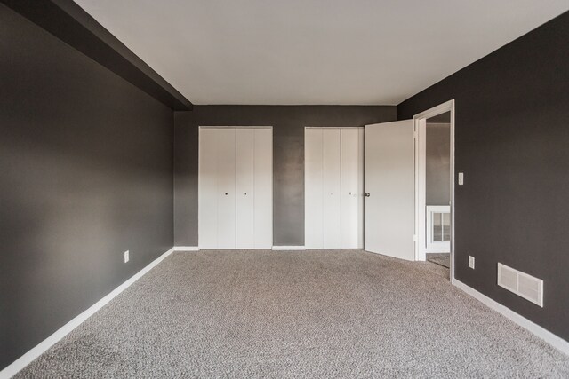 2900 E Jefferson Ave # A2, Detroit, MI 48207 - unfurnished bedroom featuring two closets, carpet, and baseboards