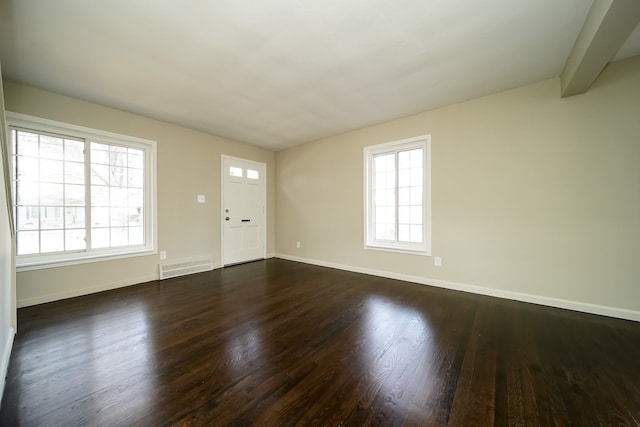 empty room with beamed ceiling, plenty of natural light, and dark wood-type flooring