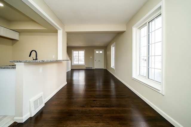 corridor featuring dark hardwood / wood-style floors, a baseboard heating unit, and sink