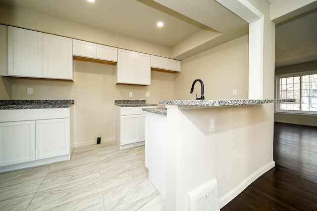 kitchen featuring sink, stone countertops, light hardwood / wood-style flooring, white cabinets, and a center island