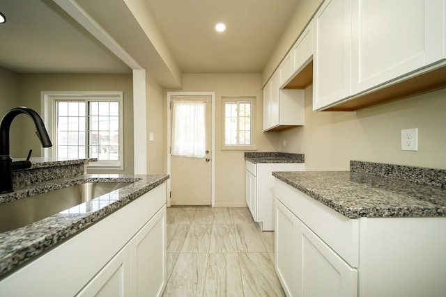 kitchen featuring white cabinets, stone countertops, and sink