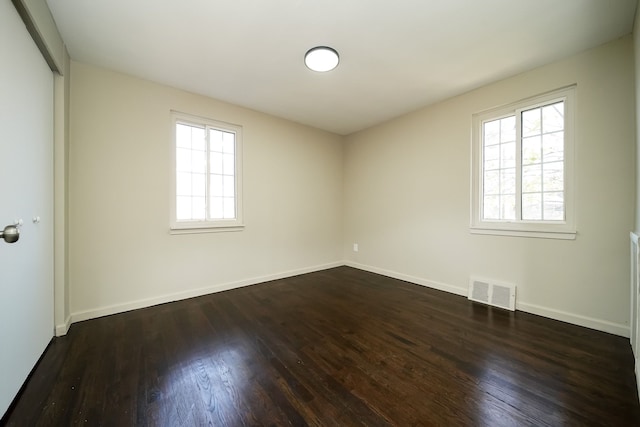 empty room with plenty of natural light and dark wood-type flooring