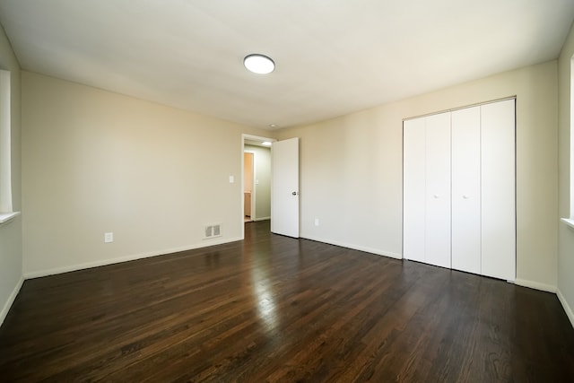 unfurnished bedroom featuring dark wood-type flooring and a closet