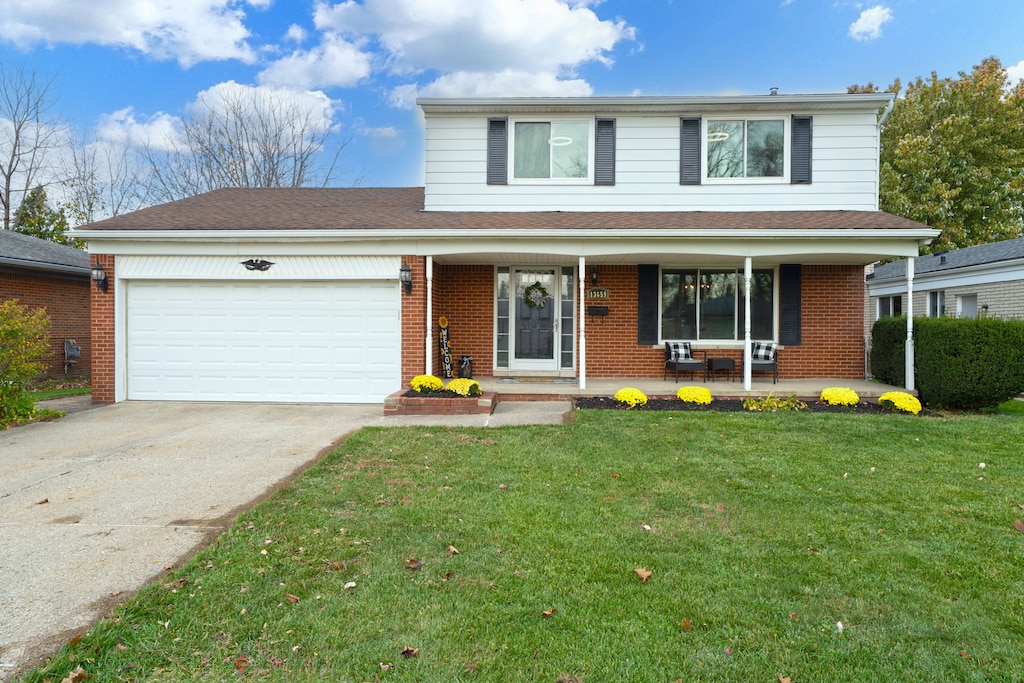 front of property with a garage, covered porch, and a front yard