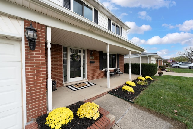 doorway to property featuring a porch, a garage, and a yard