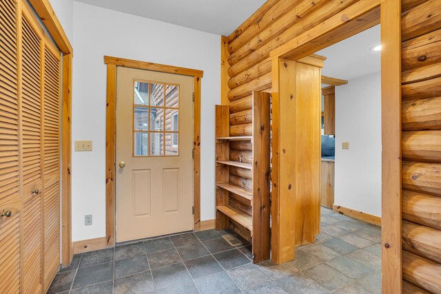 10560 Plaza Ct, Jerome, MI 49249 - entryway with dark stone finish flooring, baseboards, and rustic walls