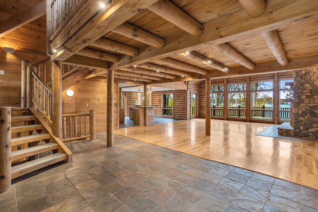 10560 Plaza Ct, Jerome, MI 49249 - unfurnished living room with wooden ceiling with exposed beams, stone tile flooring, wooden walls, and stairway