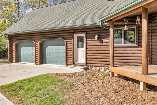 10560 Plaza Ct, Jerome, MI 49249 - view of front of house with log siding, concrete driveway, an attached garage, and a shingled roof