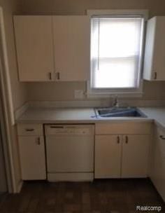 kitchen featuring dishwasher, sink, and white cabinets