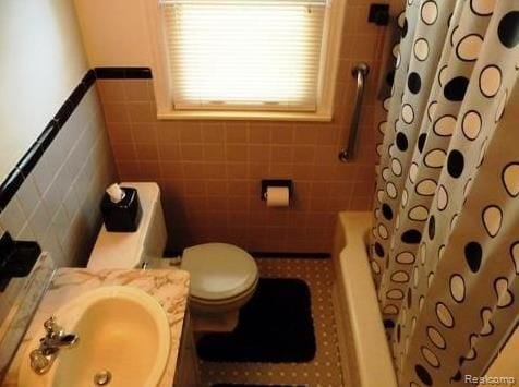 full bathroom with shower / bath combination with curtain, toilet, sink, and tile walls