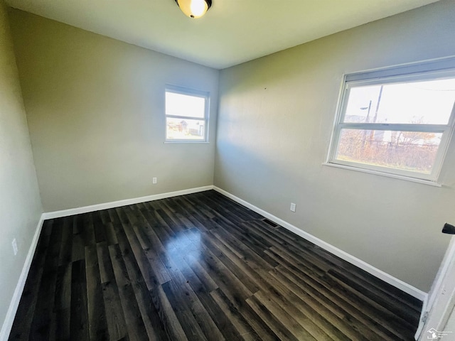 unfurnished room with dark hardwood / wood-style floors and plenty of natural light