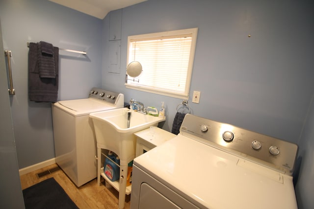 clothes washing area with washer and clothes dryer, light hardwood / wood-style floors, and sink