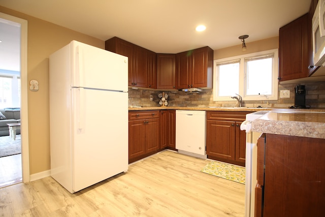 kitchen featuring decorative backsplash, light wood-type flooring, white appliances, and sink