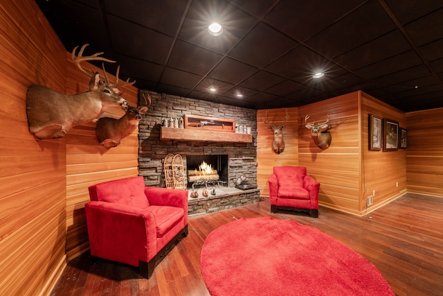 sitting room featuring hardwood / wood-style floors, wood walls, and a fireplace