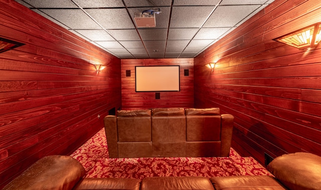 home theater featuring a drop ceiling and wood walls