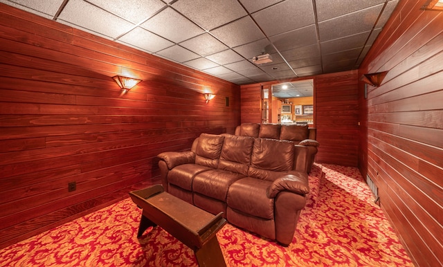 carpeted cinema room with a drop ceiling and wood walls