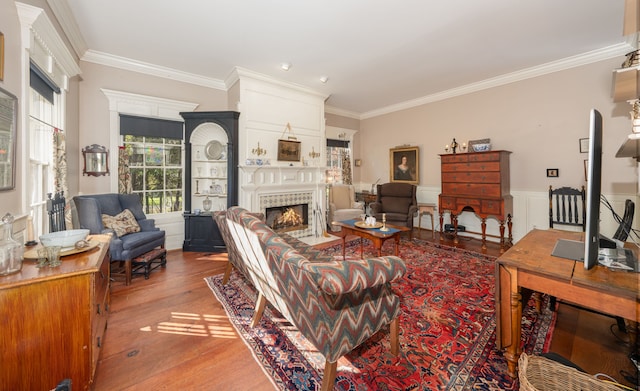 living room with a tiled fireplace, crown molding, and light wood-type flooring