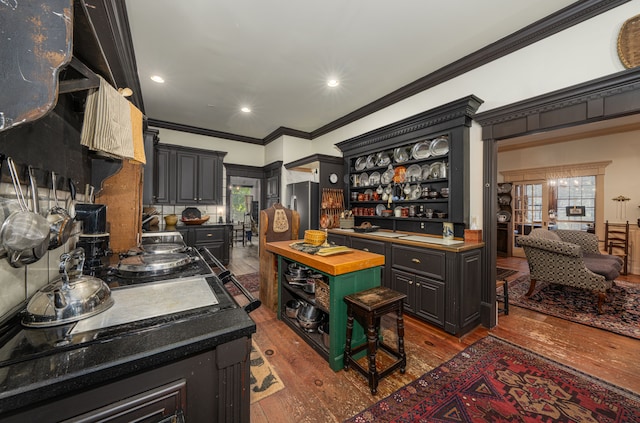 kitchen with wooden counters, dark hardwood / wood-style flooring, crown molding, a center island, and stainless steel refrigerator