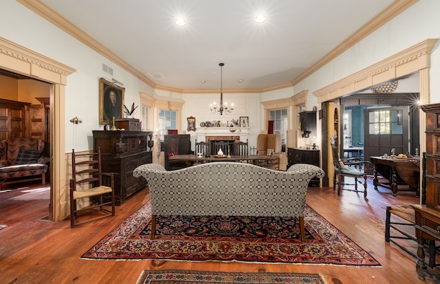 living room with a chandelier, wood-type flooring, and crown molding