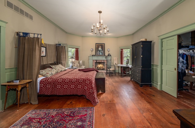 bedroom with dark hardwood / wood-style floors, a tiled fireplace, crown molding, and multiple windows