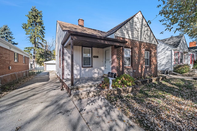 view of front facade featuring a porch, a garage, and an outbuilding